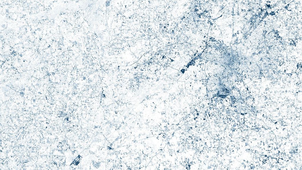 A false-color satellite image of Atlanta's metropolitan area showing urban development as dark blue patterns against a white background representing forested areas. The image was created using green wavelength measurements from Landsat satellite data to emphasize the contrast between developed and rural regions.