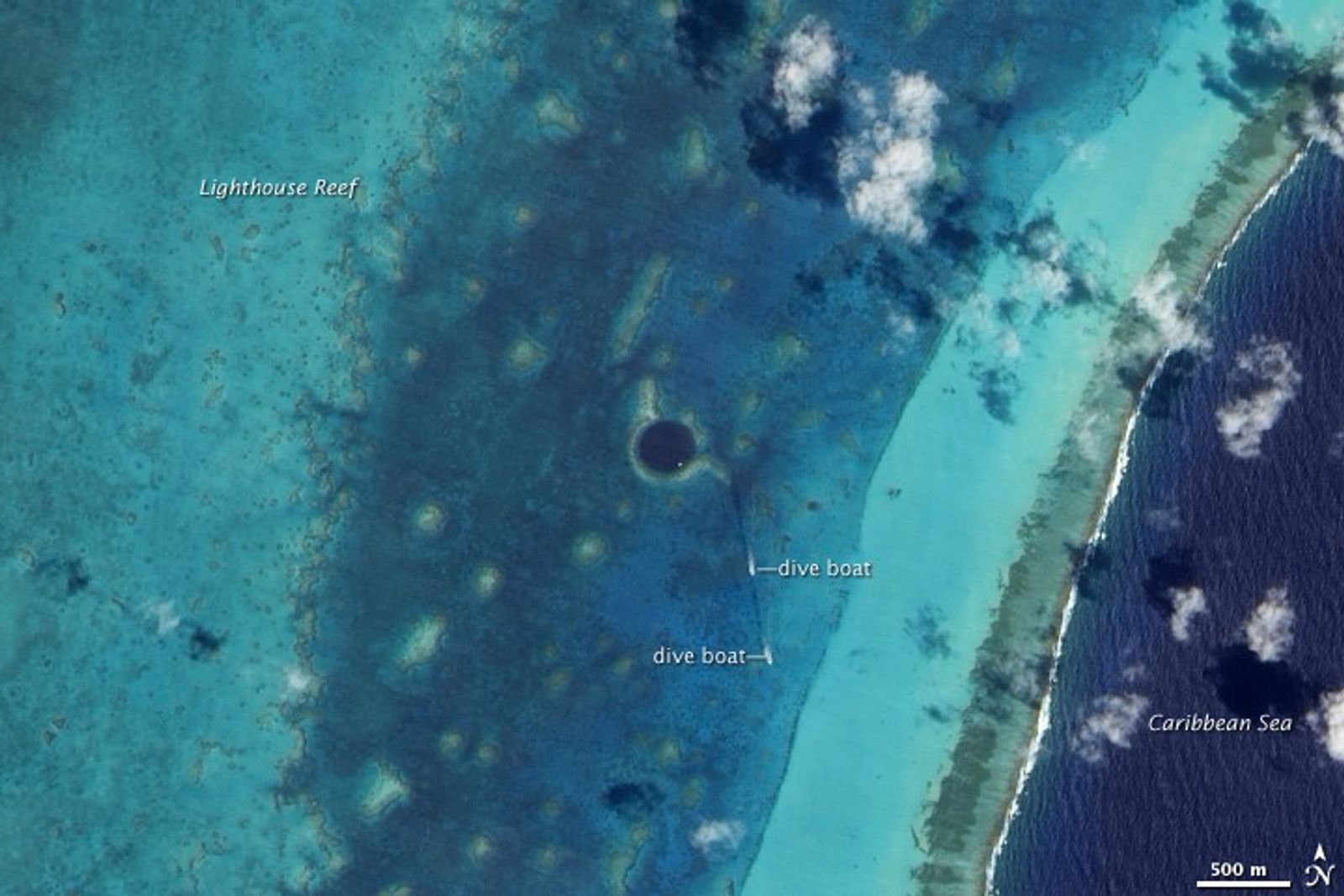 Satellite image of the Great Blue Hole, a large dark circular sinkhole surrounded by the pale turquoise shallows of Lighthouse Reef, Belize.
