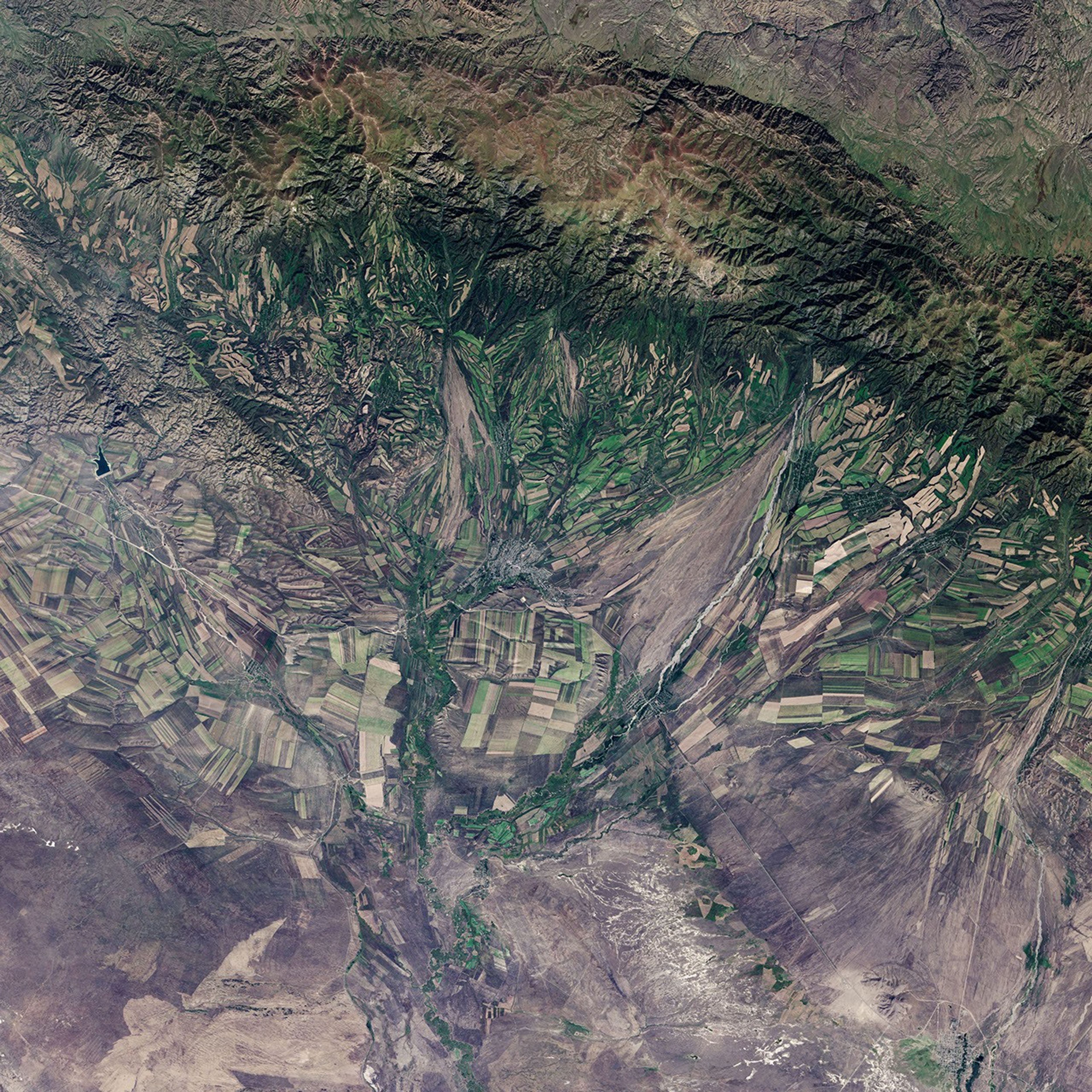 September 22, the autumnal equinox, marks the beginning of fall in the Northern Hemisphere, but the fall harvest begins early in the harsh continental climate of eastern Kazakhstan. By September 9, 2013, when the Operational Land Imager (OLI) on the Landsat 8 satellite acquired this image, several fields were already harvested and bare. Others were dark green with pasture grasses or ripening crops. The fields fill the contours of the land, running long and narrow down mountain valleys and spreading in large squares over the plains. Agriculture is an important segment of the economy in Kazakhstan: the country’s dry climate is ideal for producing high quality wheat for export. However, 61 percent of the country’s agricultural land is pasture for livestock. The area shown in this image, far eastern Kazakhstan near the Chinese border, is a minor wheat-growing region and may also produce sunflowers, barley, and other food crops. An artifact of Soviet-era collective farms, most of the farms in Kazakhstan are large, covering more than 5,000 hectares (12,500 acres). Some of the larger fields in the image reflect the big business side of agriculture. However, family farms and small agriculture businesses account for 35 percent of the country’s agricultural production, and some of these are visible as well, particularly in the uneven hills and mountains. Nearly all agriculture in Kazakhstan is rain fed. Farmers in this region have designed their fields to take advantage of rain flowing down hills, allowing the natural shape of the land to channel water to crops. The effect is a mosaic of green and tan with tones matching the natural vegetation in the mountains to the north.