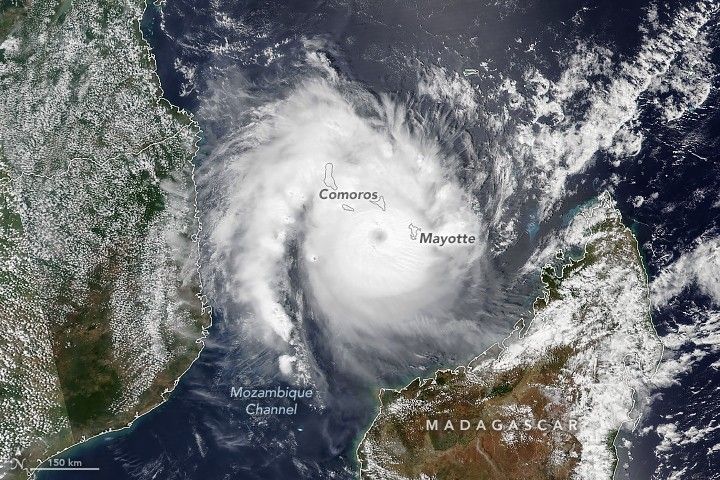 A spiral of white clouds nearly covers the entire Mozambique channel. Madagascar appears in the lower right of the image, Indian Ocean to it's right, the channel to the left. Mainland Africa frames in the left side of the image. The border outlines of the Islands of Mayotte and Comoros are superimposed on top of the Cyclone clouds, near the dark spot eye of the cyclone, but above it on either side.