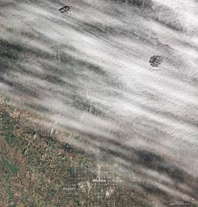 A light blanket of white clouds cover the land north of Wichita. There are two cloud holes, the one on the right is labeled a Cavum.