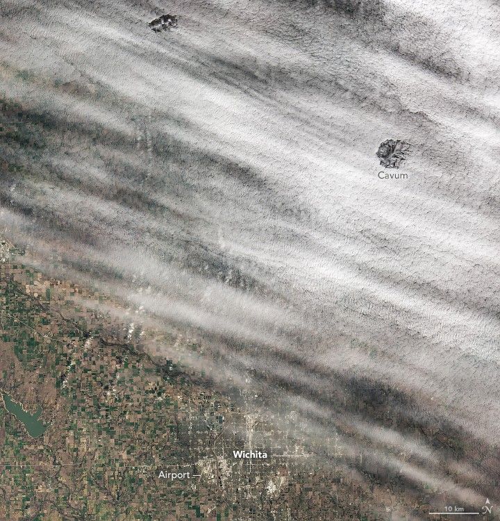 A light blanket of white clouds cover the land north of Wichita. There are two cloud holes, the one on the right is labeled a Cavum.