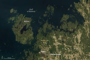 Finland's coast along the Gulf of Bothnia, which is near black in color, is shown. There are numerous islands along the coast, most notably Björkö. The land on the islands and much of mainland Finland is covered in a somewhat dulled shade of green. Streaks of land appear lighter in shade, beige to light green, where people are farming the land. Among them, near the mainland coast below Björkö is the City of Vaasa with Vanha-Vaasa, labeled more inland.
