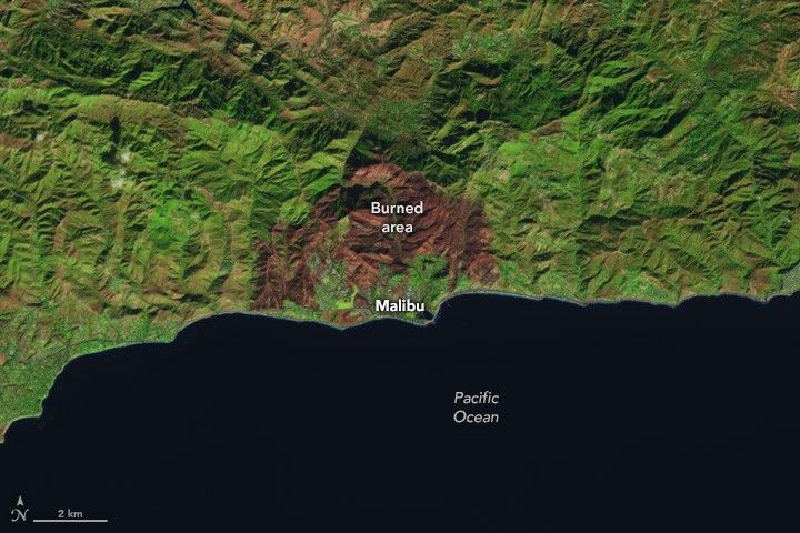 The green mountainous coastline, with the near-black Pacific Ocean occupying the lower third of the image, is interrupted by a deep rust brown surrounding the Malibu area.