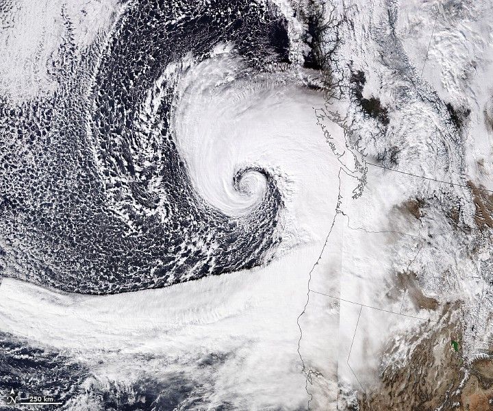 Dense swirling clouds are shown, centered off the coast of Washington State. The Dense clouds channel into the coastal region around Northern California and nearly fully obscure Washington and Nevada.