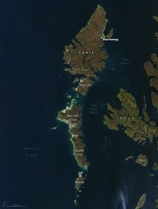 Image of island chain arc in the dark blue Atlantic Ocean. The land is a blend of green to brown shades. The water that separates these islands from more mainland areas is labeled The Minch and The Little Minch. Skye and Rum are inland islands, shown right. The archipelago consists of Stornoway on the largest land section, Lewis, and downward from there is Harris, North Uist, South Uist and finally Barra.