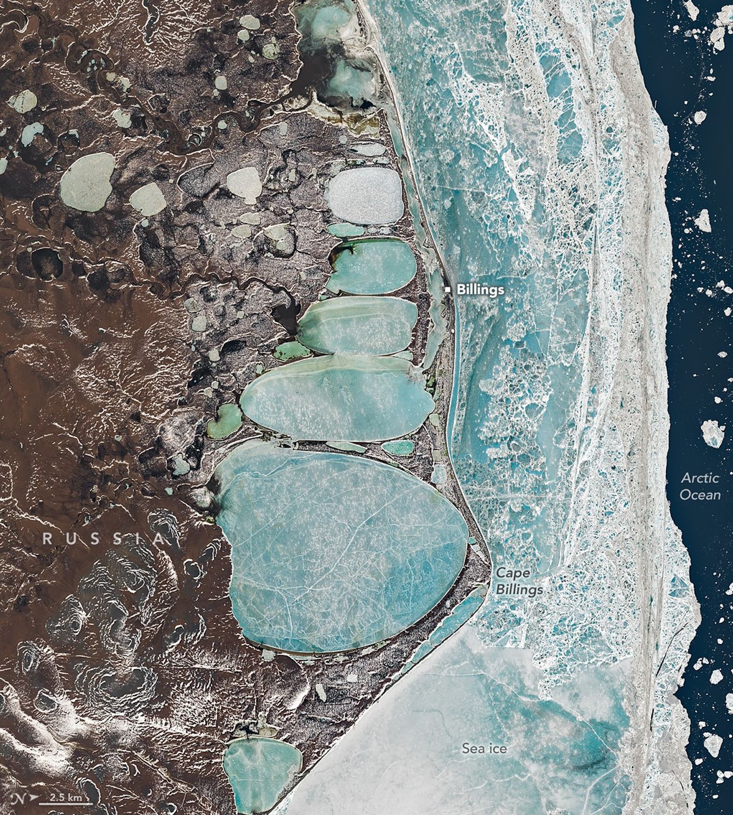A Landsat image of Russia’s Chukchi Peninsula shows a narrow coastal sandspit separating the Arctic Ocean from a chain of elongated, ice-covered coastal lagoons near the village of Billings and Cape Billings. The pale blue lagoons vary in size and line up end-to-end, creating a shape that resembles a snowman pressed against the shoreline. Offshore, fractured sea ice forms a bright, textured band along the coast, while darker tundra and thermokarst lakes extend inland.