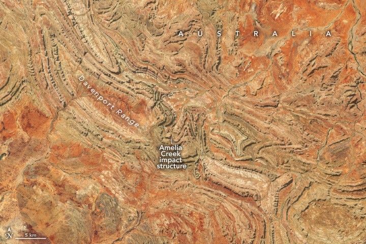 Orange to beige colored landscape covered in ridges that primarily move diagonally from top left to lower right. This is the Davenport Range, in the middle of the range and this image there is significant change in the direction of the ridges at the Amerlia Creek impact structure.