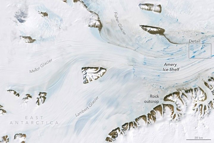 vibrant blue streaks sppear on the Amery Ice shelf. The image of East Antarctica is otherwise white with snow cover, including the Fisher Glacier at the top, the Mellow Glacier on the left, and the Lambert Glacier on the lower left. These three all converge at the Amery Ice Shelf. There are some exposed rocks visible as well, a line of them, labeled rock outcrop at the bottom of the image, runs parallel to the ice shelf.