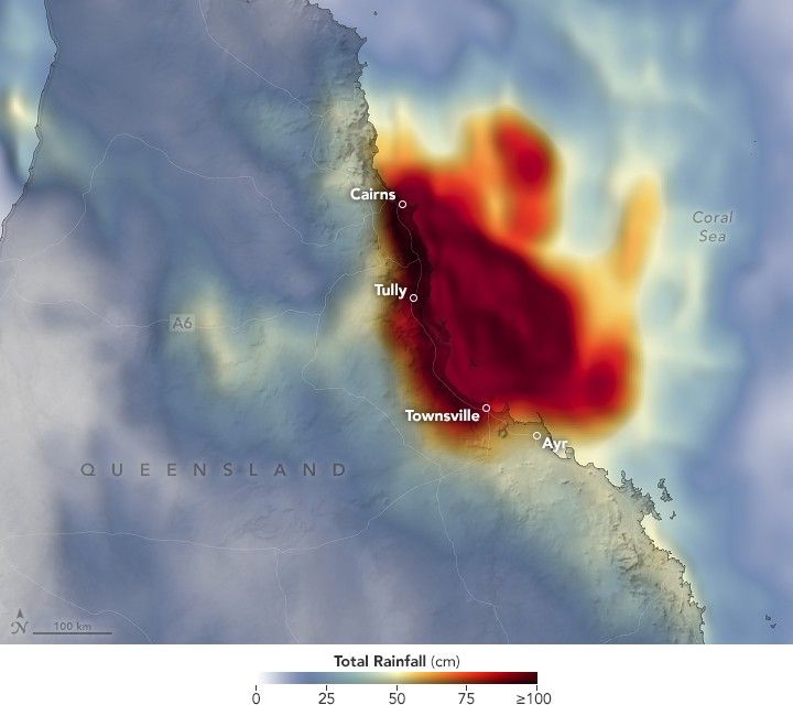 A rainfall data color gradient is overlayed over Queensland Australia. The range of rainfall data spans zero to 100 or more centimeters. The corresponding colors range from light blue to dark red. The coastal region, including the cities of Cairns, Tully, and Townsville are encompassed in a dark red blob of precipitation that mostly precipitated over the Coral Sea to the right.