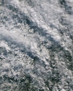 White snowy landscape of New South Wales, including Walcha and Woolbrook are partially obscured by white puffy clouds.