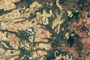 Fields in Brazil are primarily divided into rectangles but include circular fields of vibrant green. The right side of the image has far fewer fields and is filled with a craggy naturally foliated landscape.