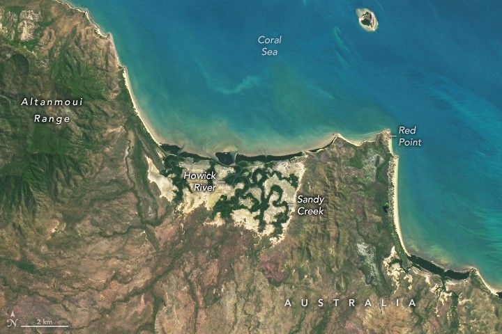 The coral sea, light blue, occupies the upper right half of the image, with Australia occupying the lower left. The Altanmoui  Range is labeled in the upper left corner, the peaks appear sage green with the land to the right being more sandy and beige. Howick River and Sandy Creek near the coast are more green in color and the land a lighter shade, more like the coastal sand at Red Point right of these rivers.