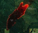 amid an image full of a variety of shades green of foliage there is a dark swath labeled burned area outlined by a bright red and yellow colored area labeled active fire via infrared heat signature. The more upper right portion of the image has the widest and most vibrant red and yellow active fire