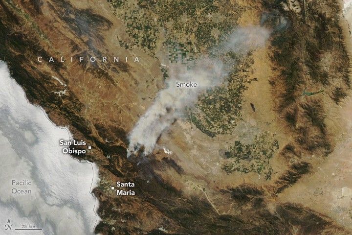 Smoke emanates from the hills inland of and between coastal towns San Luis Obispo and Santa Maria. The smoke travels inland over the California Valley , covered in farmed fields and surrounded by arid terrain.