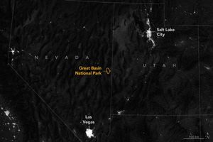 The nighttime view of the Western United States with state boundary overlay includes the city lights of Salt Lake City and Las Vegas and a few small outcroppings of lights. In the midst of the darkest region is an orange outline for the borders of Great Basin National Park.