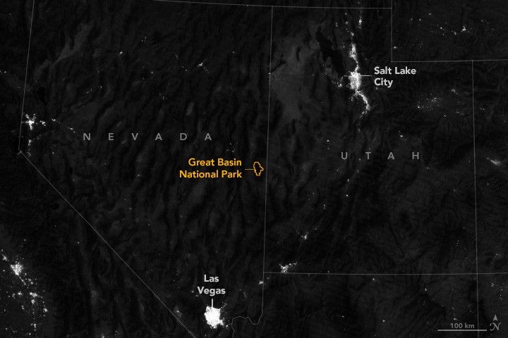 The nighttime view of the Western United States with state boundary overlay includes the city lights of Salt Lake City and Las Vegas and a few small outcroppings of lights. In the midst of the darkest region is an orange outline for the borders of Great Basin National Park.