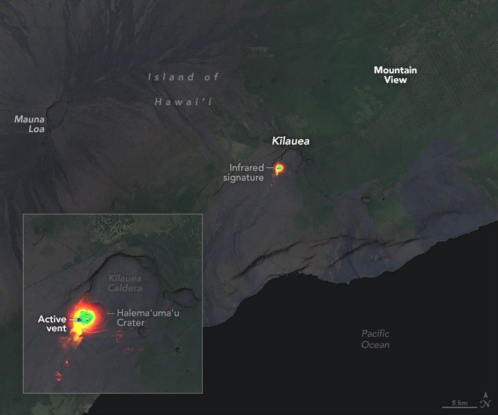 The gray landscape along the coastline includes Mauna Loa, in the upper left, a crater with streaks of darker land coming away from it, and Mountain View, which is expansive green tinted space. Between them and slightly lower and closer to the coast is a bright orange spot, Kilauea, labeled as an infrared signature. The Pacific Ocean is in the lower right and appears black in this image. The zoom in box in the lower left shows the infrared signature of Kilauea is in the lower left corner of the Kilauea Caldera. This is labeled Halema‘uma‘u.