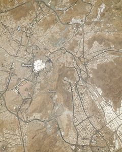 The light brown sandy region centers a bright white building labelled Mosque. There are sprawling major roadways across the region with significant human settlements around them. In the lower part of the image are tunnels, directly below the Mosque. and the lower right shows large blocks of white labeled tents.