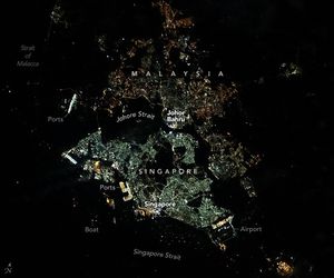 The Johore Strait separates Singapore (south) from Peninsular Malaysia (north). The urban area of Singapore encompasses the country’s main island, Singapore Island, in addition to numerous smaller islands scattered throughout the Johore and Singapore straits. Two illuminated bridges, the Johor Causeway in the central region and the Second Link toward the west, connect the two countries. The Strait of Malacca on the top-left side of the image appears dark, lacking much light from boats or land, whereas the right side is lined with small villages of mainland Malaysia.