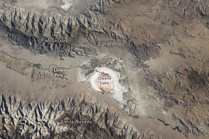 a white spot with an orange colored center resides in the valley between the Inyo Mountains, at the top of the image, and the Sierra Nevada at the bottom. The entire landscape aside from Owen's Lake is pale brown.