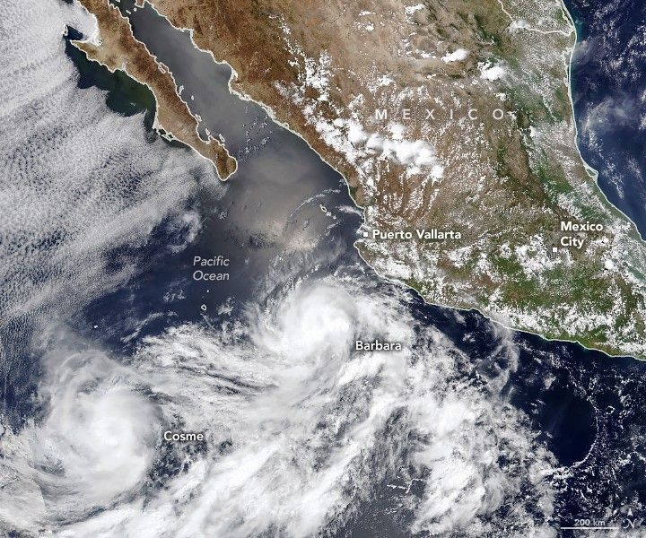 The image centers over the deep blue Pacific Ocean off the coast of Mexico. Just south and west of the coastal city of Puerto Vallarta is a swirl of clouds labeled Barbara. A separate swirl center at the bottom left is labeled Cosme, both storms clouds intermingle along the bottom of the image. A sliver of the Gulf of Mexico is visible in the upper right corner and Mexico city is labeled in the middle right of the image. Mexico city seems to be situated at the juncture where land goes from mostly beige and sandy to green, and further south continues to show increased foliage covered landscape.