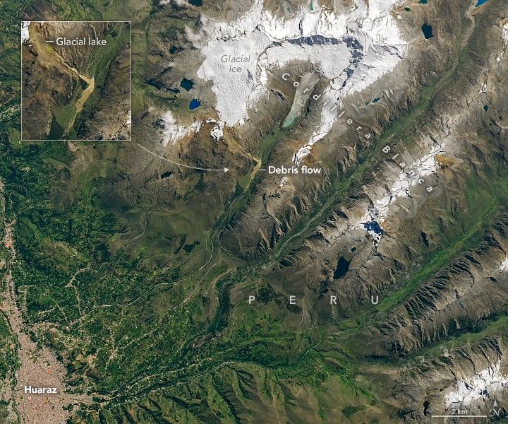 White glacial ice in the top of the image, where brown mountain peaks are located, give way to glacial lakes and debris flows in Cordillera Blanca in Peru. The brown highlighted debris flow is in the valley between two mountains which drains toward the dense population area of Huaraz, which is surrounded by the foliage that occupies the lower left of the image.