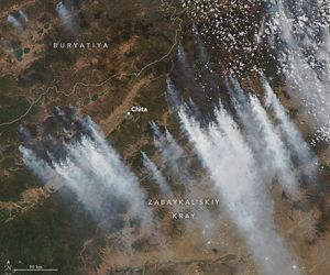 Smoke streams diagonally across the image to the lower right from numerous points along the opposite diagonal. The city of Chita is surrounded by smoke origin points on the lower, left and right. Above Chita in this image is a relatively smoke-free Buryatiya region, outlined with a gray overlay in the top left corner.