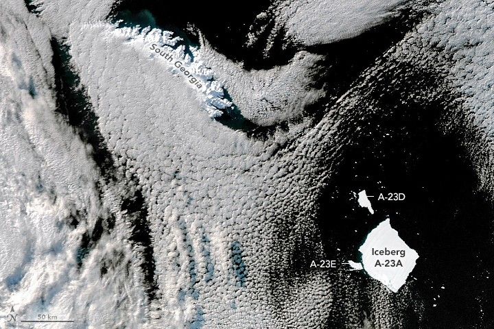 The black ocean waters are largely obstructed by cloud cover in this image, however the bright white snow covering South Georgia is visible in the upper left. Iceberg A-23A is also visible in the lower right, with A-23D floating above it and A-23E barely separated to the left of it.