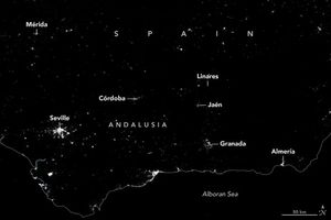A dark image with an outline border for the country of Spain dividing it from the Alboran Sea at the bottom of the image. Left to right the following cities are labeled Mérida, Seville, Córdoba, Linares, Jaén, Granada, and Almería. The city lights of these cities are all less bright than normal, Linares lights are completely missing.