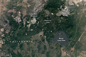 A mostly green region of California in interrupted by a black bit of land labeled burnt lava flow. Directly above that with some foliage between is a gray area labeled Glass Mountain. To the left of glass mountain is more foliage and another gray area labelled Little Glass Mountain. Medicine lake also sits equidistant between the two mountains.