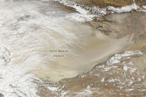 The Takla Makan Desert is covered in a light beige dust partially covered in white clouds, mostly at the left of the image. China is labelled at the bottom right corner of the image.