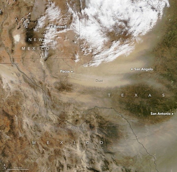 Satellite view of the West border of Texas. Sweeping dust extends from Mexico to San Antonio at the right edge of the image. Another more dense dust cloud is Labeled between Pecos Texas, directly South of Roswell New Mexico over and extending slightly past San Angelo. Clouds cover the top of the image above the dust