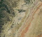 Grid-like arrays of solar panels cover parts of a valley floor in a brown, dry-looking area of Utah.