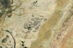 Grid-like arrays of solar panels cover parts of a valley floor in a brown, dry-looking area of Utah.