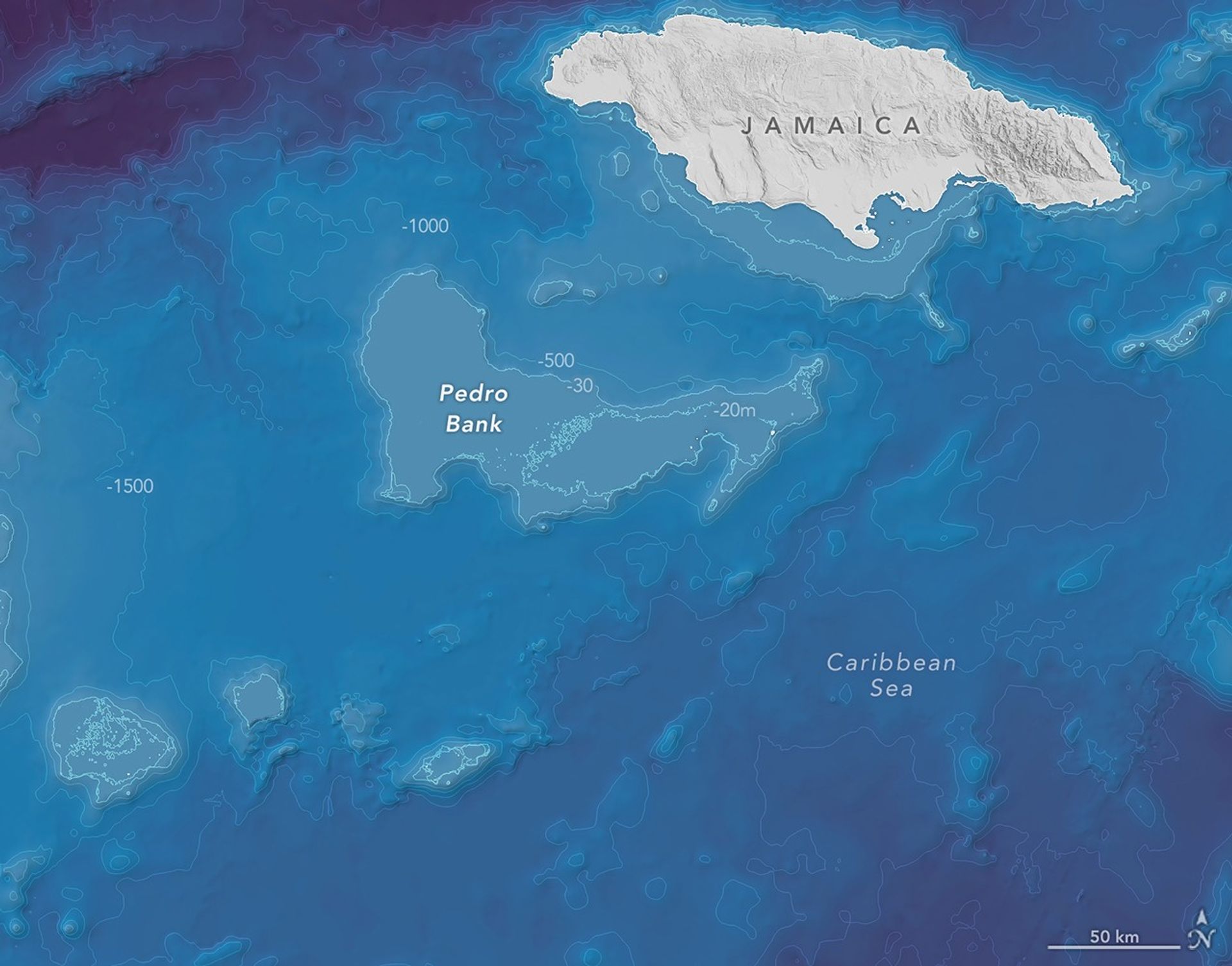 A bathymetric map of part of the Caribbean Sea shows Jamaica in the upper right and the large, flat-topped Pedro Bank at the center, which sits 20 to 30 meters below the surface and displays steep edges. Several smaller shallow shelves appear in the lower left.