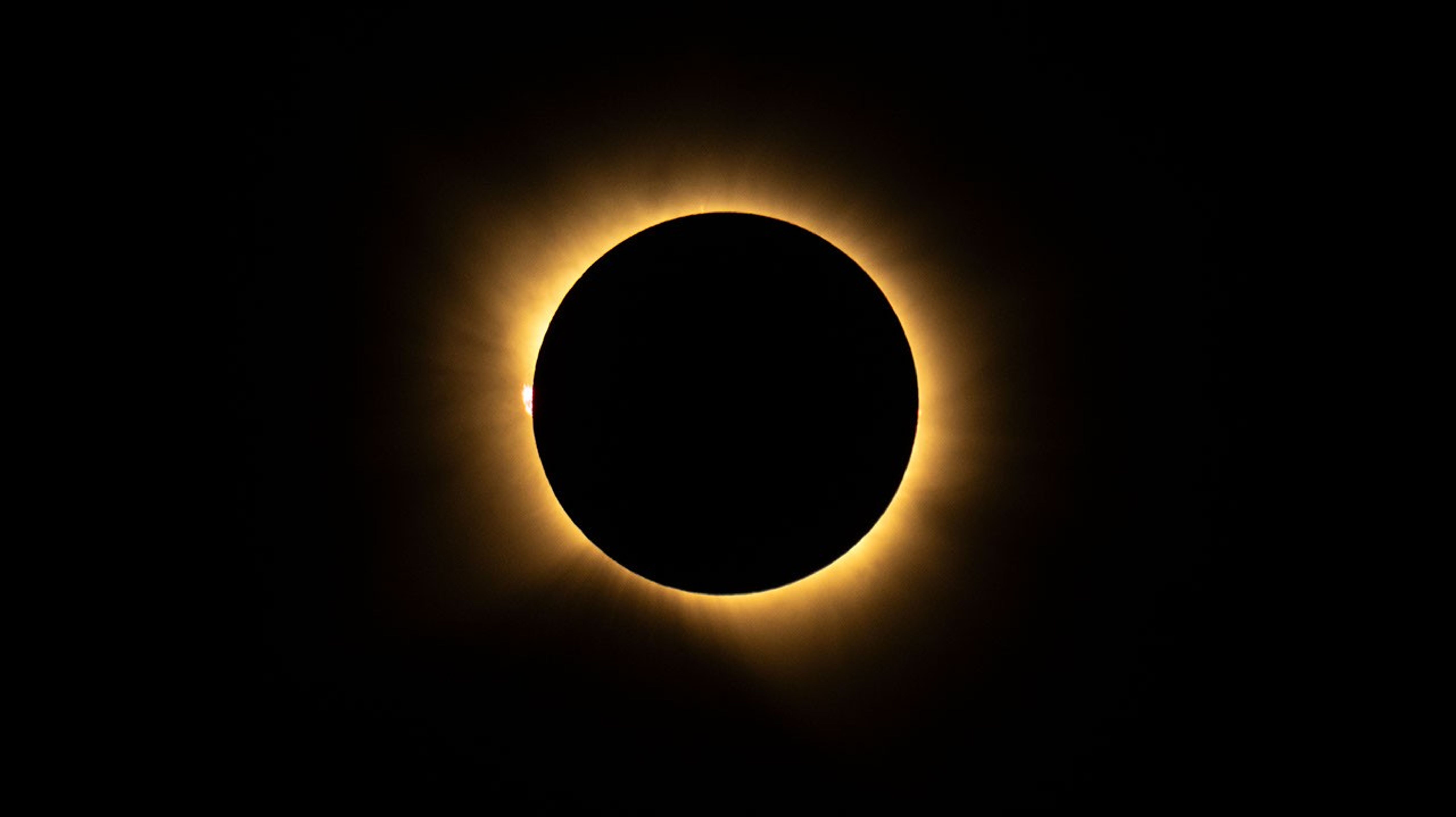 A ring of bright light shines from behind the Moon, which appears as a black circle, during a total solar eclipse.