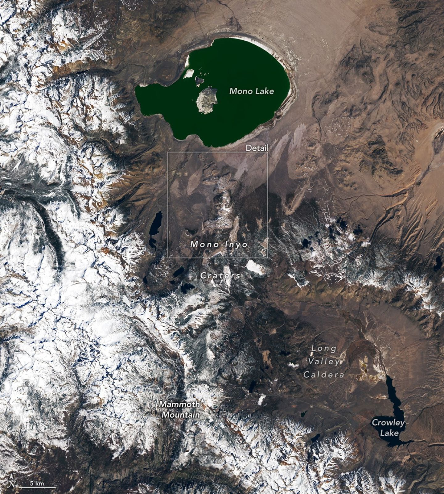 A string of small, partially snow-covered volcanic craters runs north-south between Mono Lake and Mammoth Mountain. Snowy mountains fill the left side of the image.
