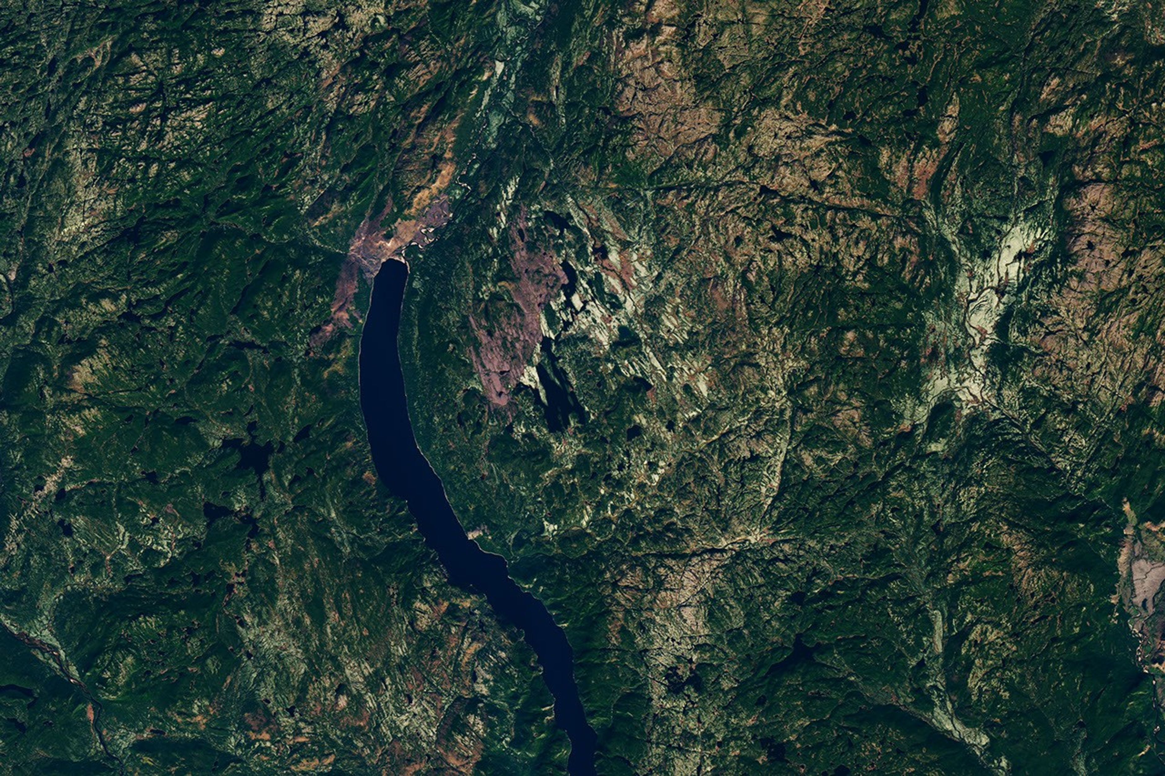 Though subtle, a circular indentation with Lake Marsal near the center is visible in the middle of a mostly green landscape with textured terrain and many lakes.