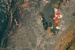 An aerial view of the San Francisco Bay Area Stadium, middle-left, is surrounded by urban infrastructure. Colorful ponds of the southern San Francisco Bay are visible toward the top.
