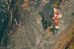 An aerial view of the San Francisco Bay Area Stadium, middle-left, is surrounded by urban infrastructure. Colorful ponds of the southern San Francisco Bay are visible toward the top.