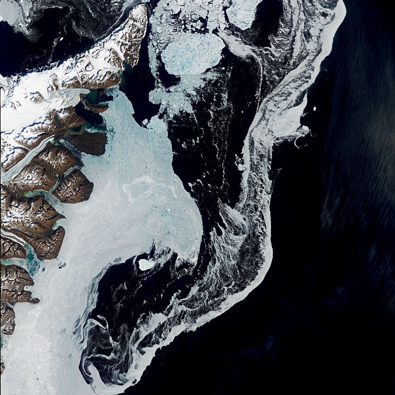 A satellite image shows the dark blue waters of the Denmark Strait with swirling sea ice to the right of eastern Greenland. A bright white iceberg sits amid the sea ice in the middle-left of the scene.