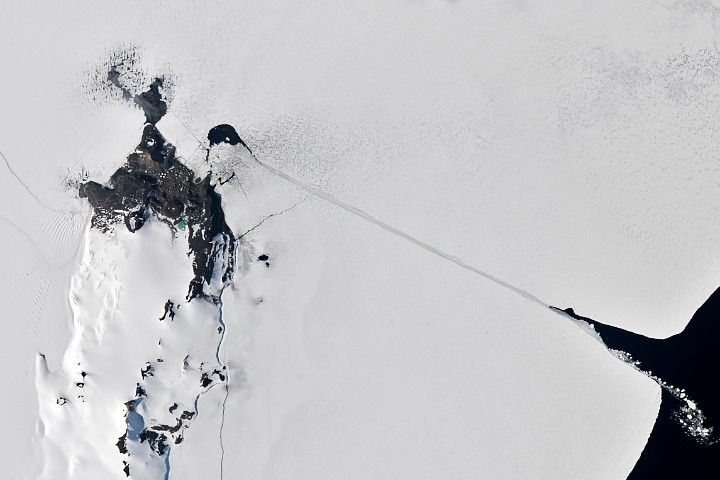 A satellite image of the same area shows a completed channel cut by an icebreaker through the sea ice. The ship channel stretches about 10 kilometers from open water on the right to McMurdo Station on the left.