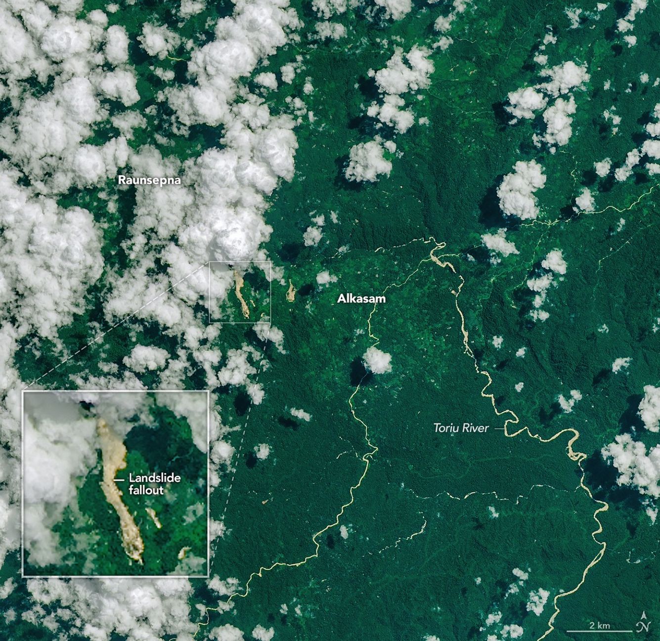 A narrow, light-brown landslide scar cuts through dark green forested mountains in East New Britain and extends south toward a stream valley. Rivers swollen with floodwaters, areas of forest clearing, and scattered clouds are also visible in some parts of the image.