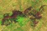 A brown patch of burned vegetation is visible on the landscape surrounding two reservoirs in a hilly region west of Madrid.