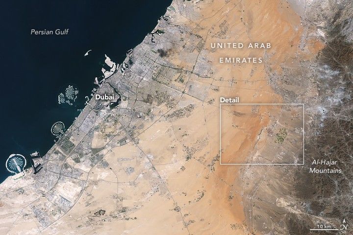 Development associated with Dubai appears as a light gray zone along the coast of the Persian Gulf with the dark gray Al-Hajar Mountains on the far right side of the image. A ridge lies in the middle of the image in a sandy area.