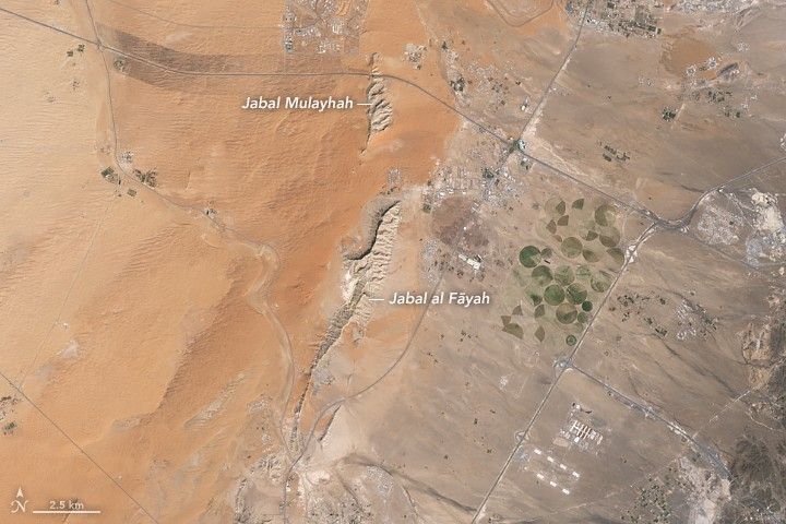 Limestone ridges appear as linear features running north–south with orange-toned desert to the west and a darker-toned mountain range to the east.