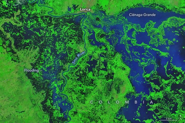 A false-color satellite image captured on February 9, 2026, shows extensive flooding along the Sinu River near Lorica. Dark floodwaters are visible against the green landscape on both sides of the river but especially to its east.