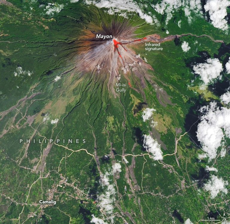 Imagem de satélite do vulcão Mayon nas Filipinas mostrando encostas marrons próximas ao cume, vegetação verde nas partes baixas e uma assinatura térmica vermelha indicando lava e calor vulcânico