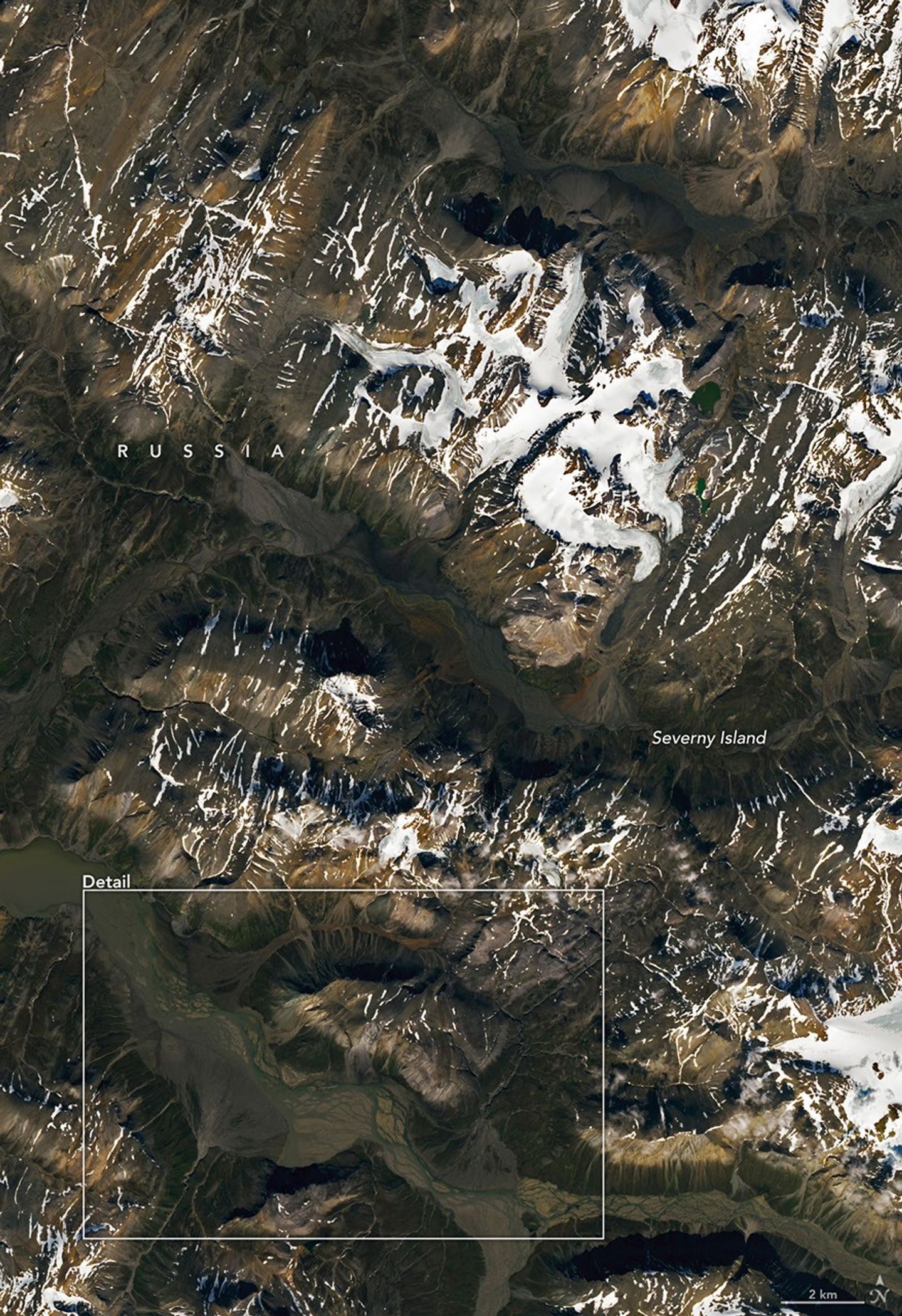 Ice-capped mountains are interrupted by broad valleys lined with alluvial fans.